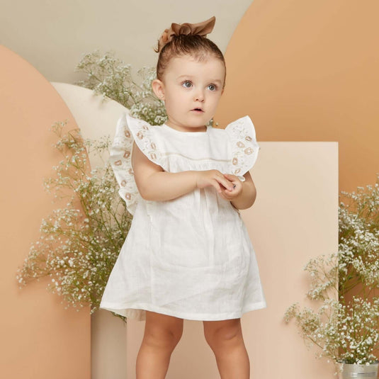 Vestido y pantalón beige para bebé con estampado sutil y tejido suave.