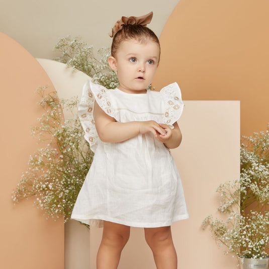 Vestido y pantalón beige para bebé con estampado sutil y tejido suave.